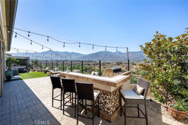 view of patio featuring a mountain view, exterior bar, grilling area, and an outdoor kitchen