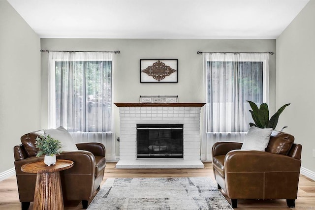 living area featuring light hardwood / wood-style flooring and a brick fireplace