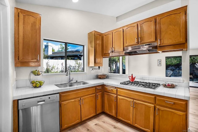 kitchen featuring kitchen peninsula, stainless steel appliances, tile countertops, light hardwood / wood-style flooring, and sink