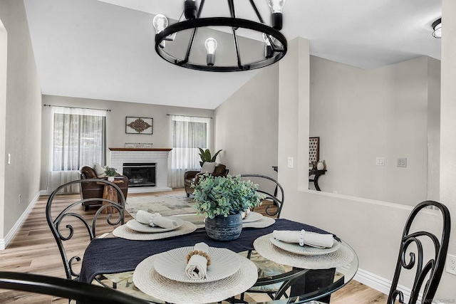 dining area with an inviting chandelier, light hardwood / wood-style floors, and lofted ceiling