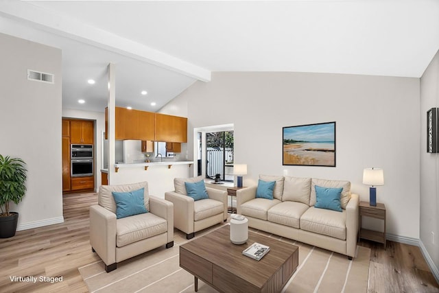 living room with light wood-type flooring, beam ceiling, sink, and high vaulted ceiling