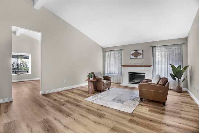 living room featuring light hardwood / wood-style flooring, a brick fireplace, beamed ceiling, and high vaulted ceiling