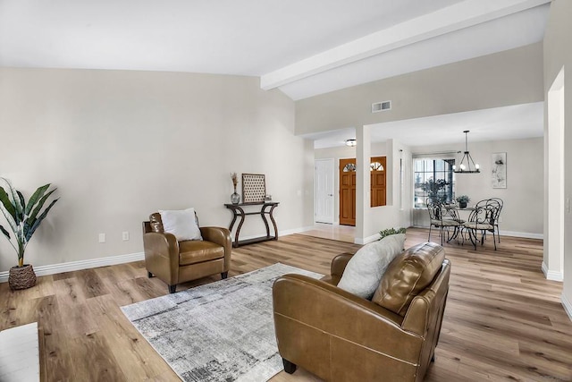 living room featuring an inviting chandelier, vaulted ceiling with beams, and light hardwood / wood-style floors