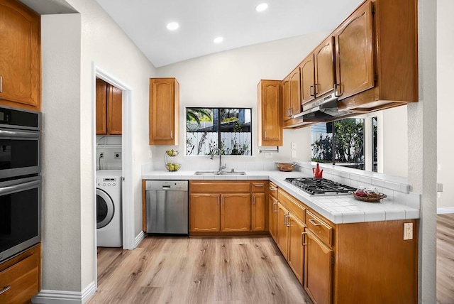 kitchen featuring washer / dryer, vaulted ceiling, appliances with stainless steel finishes, and a healthy amount of sunlight