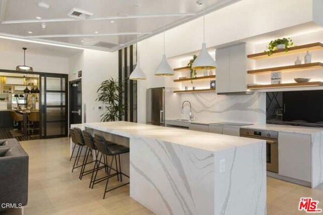 kitchen featuring hanging light fixtures, wall oven, tasteful backsplash, stainless steel fridge, and a spacious island