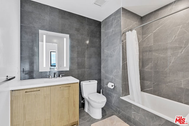 full bathroom with shower / tub combo, vanity, toilet, and tile walls