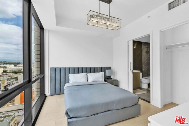 bedroom featuring ensuite bathroom, a closet, a chandelier, and light wood-type flooring