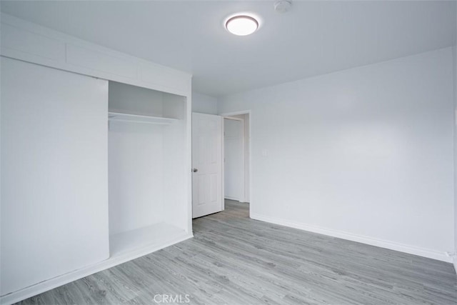 unfurnished bedroom with a closet and light wood-type flooring