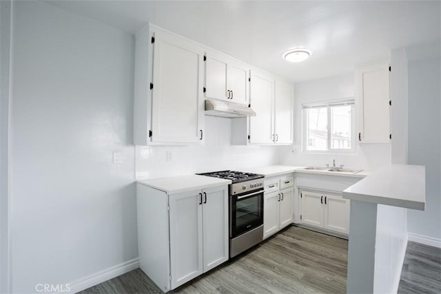 kitchen featuring sink, stainless steel stove, light wood-type flooring, white cabinetry, and kitchen peninsula