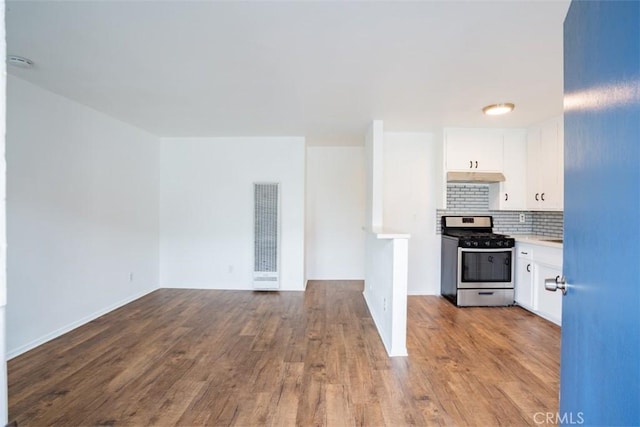 kitchen featuring decorative backsplash, white cabinetry, light hardwood / wood-style floors, and stainless steel range oven