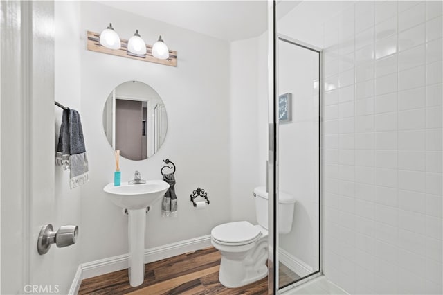 bathroom with hardwood / wood-style flooring, an enclosed shower, and toilet