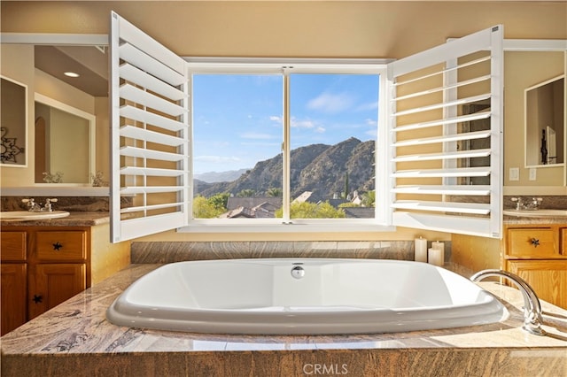 bathroom featuring a wealth of natural light, a mountain view, tiled bath, and vanity