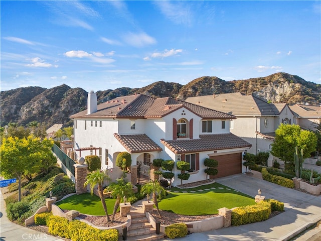 mediterranean / spanish-style home with a mountain view, a front lawn, and a garage