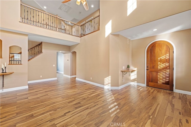 foyer entrance with wood-type flooring, a high ceiling, and ceiling fan