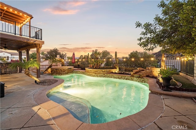 pool at dusk featuring a patio and a hot tub