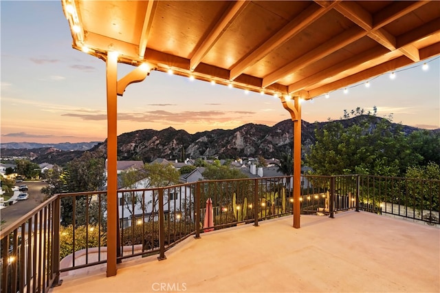 patio terrace at dusk featuring a balcony and a mountain view