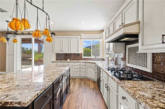 kitchen with pendant lighting, light stone counters, dark hardwood / wood-style floors, custom range hood, and decorative backsplash