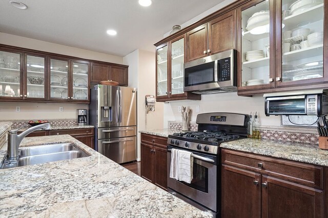 kitchen with light stone countertops, appliances with stainless steel finishes, and sink