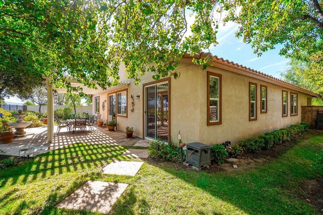 rear view of house featuring a lawn and a patio