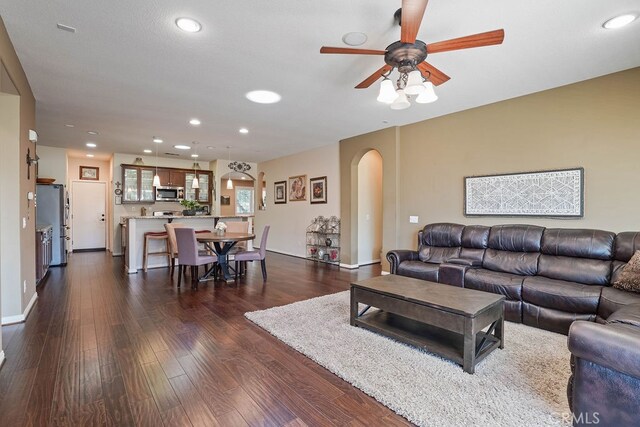 living room featuring ceiling fan and dark hardwood / wood-style flooring