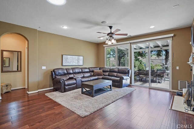 living room featuring ceiling fan, dark hardwood / wood-style flooring, and a textured ceiling