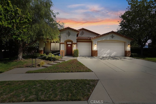 mediterranean / spanish home featuring a yard and a garage