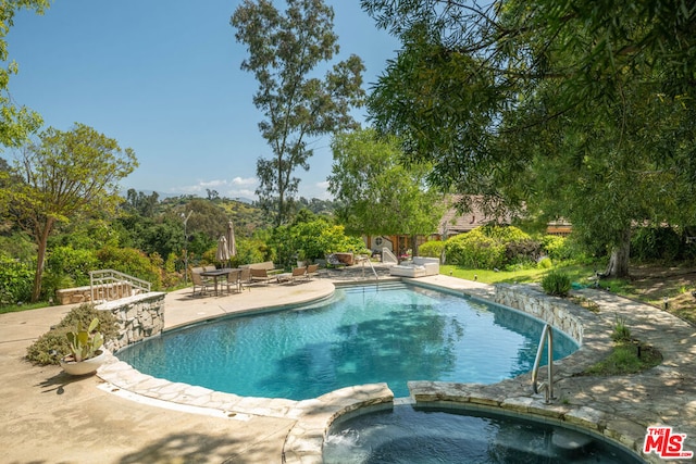 view of swimming pool featuring a patio area and an in ground hot tub