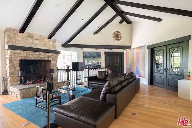 living room with a fireplace, beam ceiling, light hardwood / wood-style flooring, and a wealth of natural light