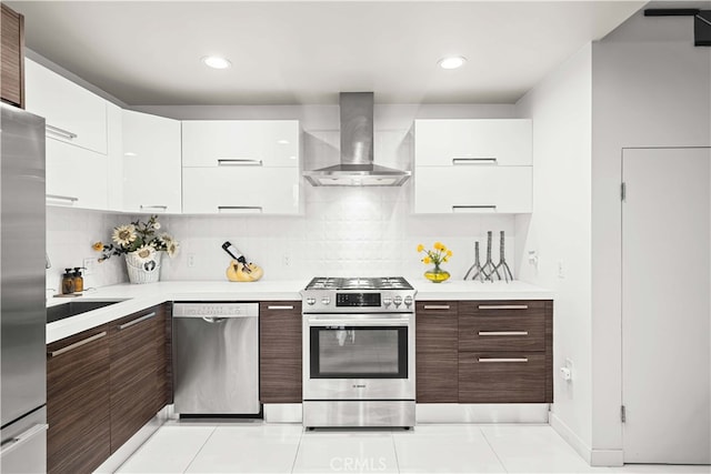 kitchen with wall chimney exhaust hood, tasteful backsplash, dark brown cabinets, white cabinets, and appliances with stainless steel finishes