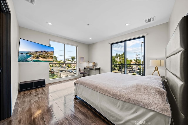 bedroom featuring dark hardwood / wood-style flooring, access to outside, and multiple windows