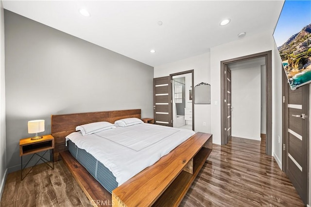 bedroom with ensuite bath and dark wood-type flooring