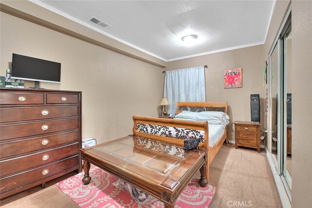 bedroom featuring a textured ceiling, crown molding, and light carpet