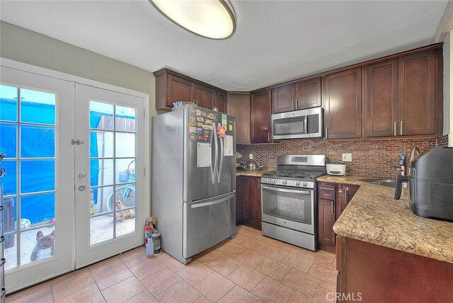 kitchen featuring appliances with stainless steel finishes, tasteful backsplash, dark brown cabinets, french doors, and sink