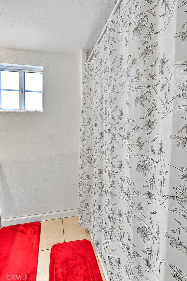 bathroom featuring walk in shower, a textured ceiling, and tile patterned floors