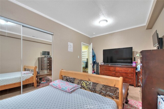 bedroom with a textured ceiling, carpet, ornamental molding, and a closet