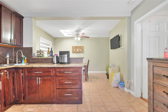 kitchen featuring light tile patterned flooring, tasteful backsplash, sink, a skylight, and ceiling fan