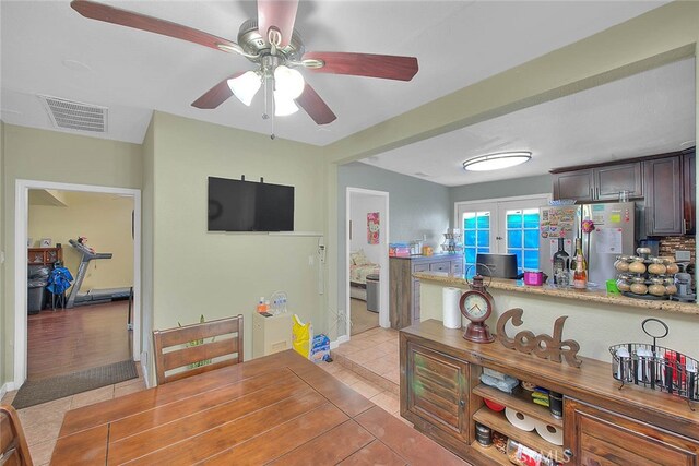 kitchen featuring dark brown cabinetry, ceiling fan, stainless steel fridge, light tile patterned floors, and french doors