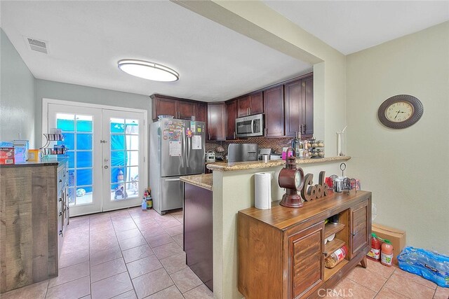 kitchen with appliances with stainless steel finishes, a kitchen breakfast bar, backsplash, kitchen peninsula, and french doors