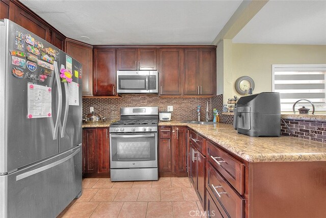 kitchen featuring backsplash, sink, stainless steel appliances, and light stone counters