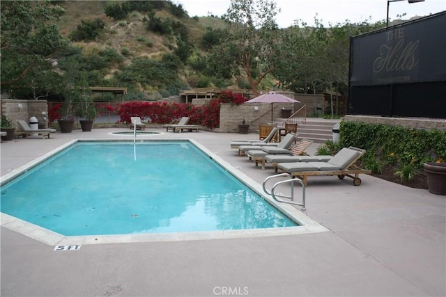 community pool featuring a patio area, fence, and stairway