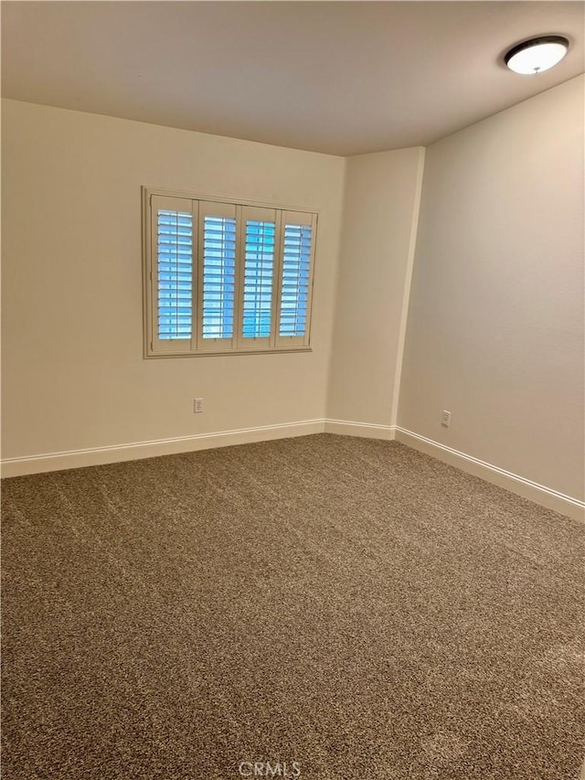 spare room featuring carpet flooring and baseboards