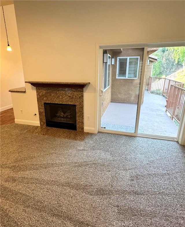 unfurnished living room featuring carpet floors, a fireplace, and baseboards