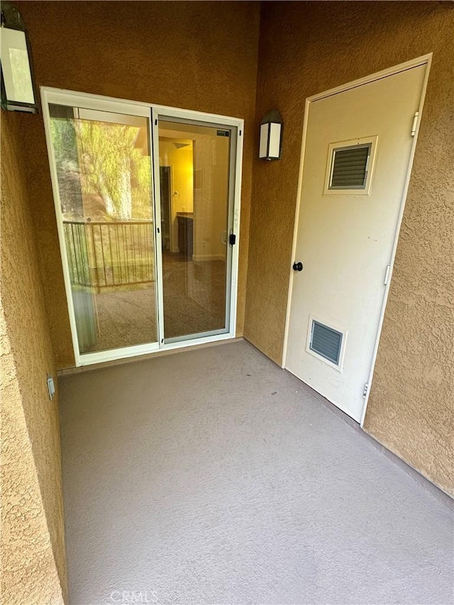 view of exterior entry featuring a patio area, visible vents, and stucco siding