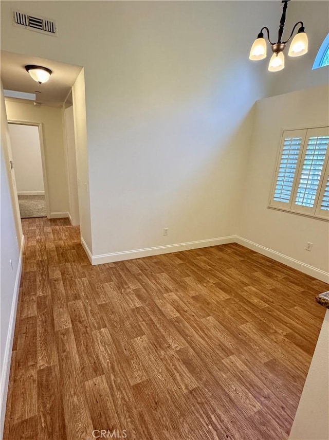 interior space with a chandelier, visible vents, baseboards, and wood finished floors