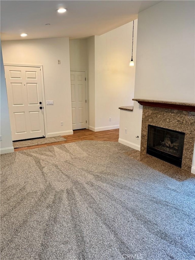 unfurnished living room with recessed lighting, carpet flooring, baseboards, and a premium fireplace