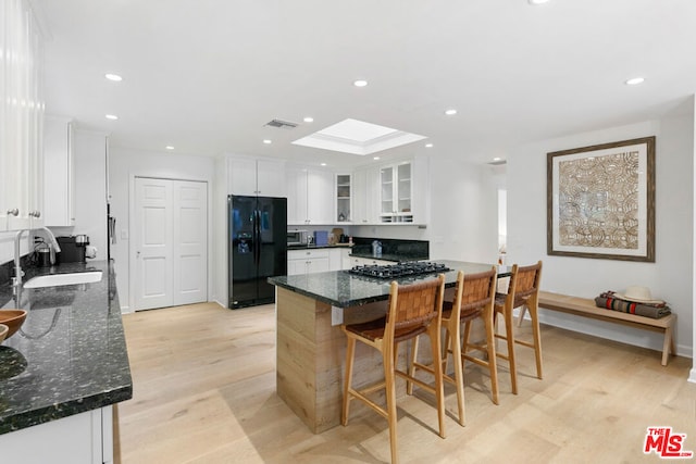 kitchen with sink, white cabinetry, stainless steel appliances, and a skylight