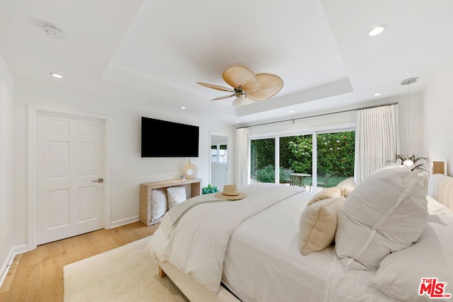 bedroom with access to exterior, ceiling fan, light hardwood / wood-style floors, and a raised ceiling