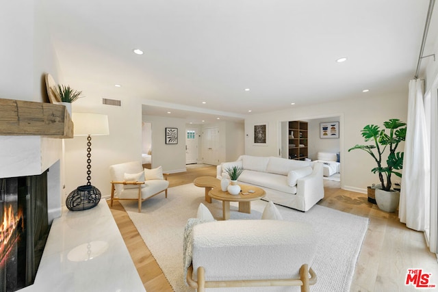 living room with a multi sided fireplace, light hardwood / wood-style floors, and a healthy amount of sunlight