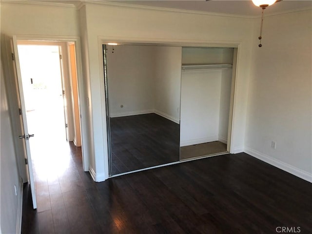 unfurnished bedroom featuring dark hardwood / wood-style flooring, a closet, and ornamental molding