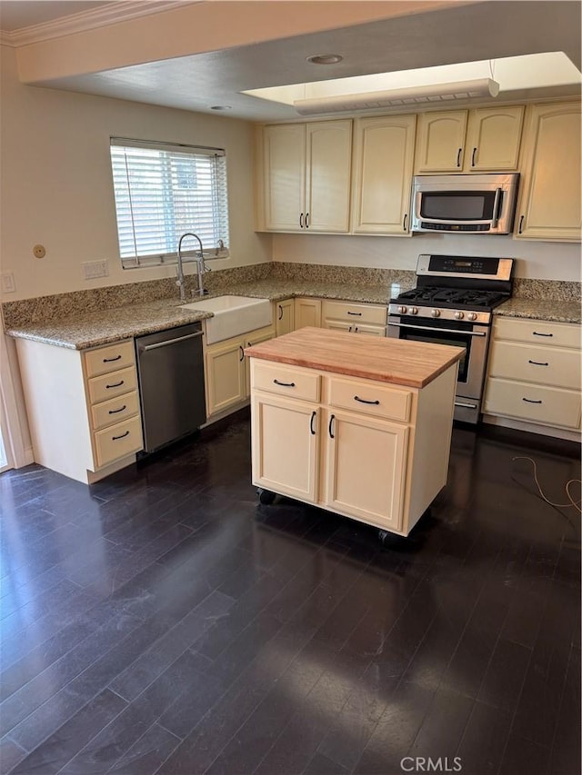 kitchen with cream cabinetry, dark hardwood / wood-style floors, sink, and appliances with stainless steel finishes